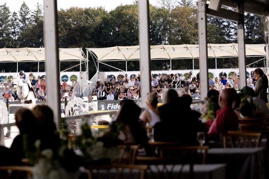 Guests at ringside tables in the hospitality tent watching a rider in Trelawny Stadium